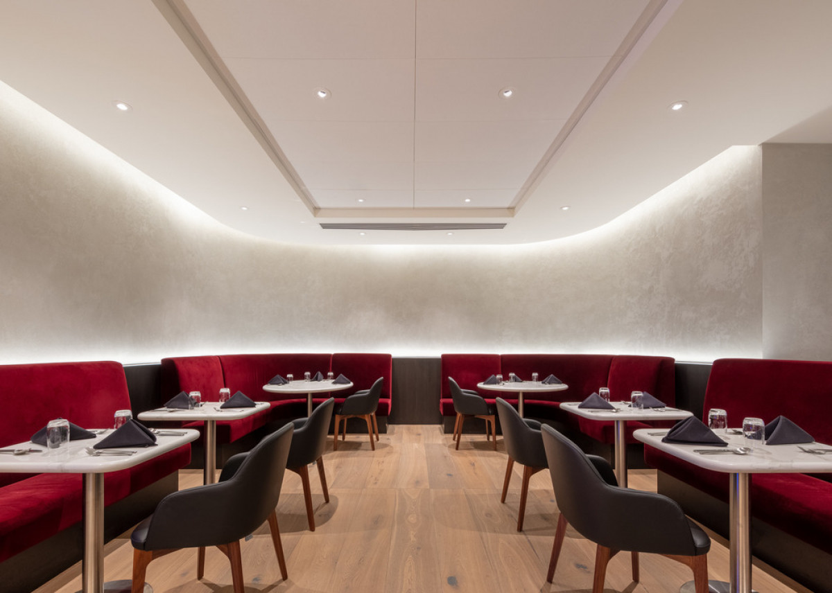   British Airways Lounge: The Boutique Dining Room captures a modern yet luxurious vibe with plush seating in red velvet and lighting design by Studio Three Twenty One. Photo credit: Eric Rorer 