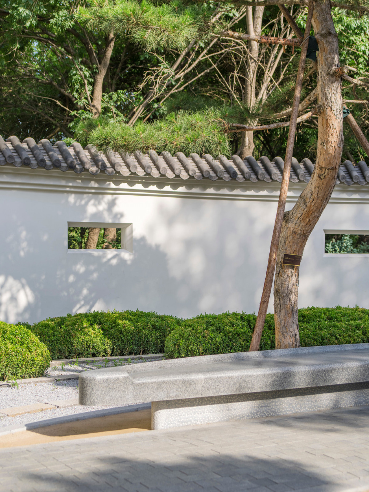 A uniquely carved stone seat provides a vantage for contemplation within the serene setting of the winter season garden.