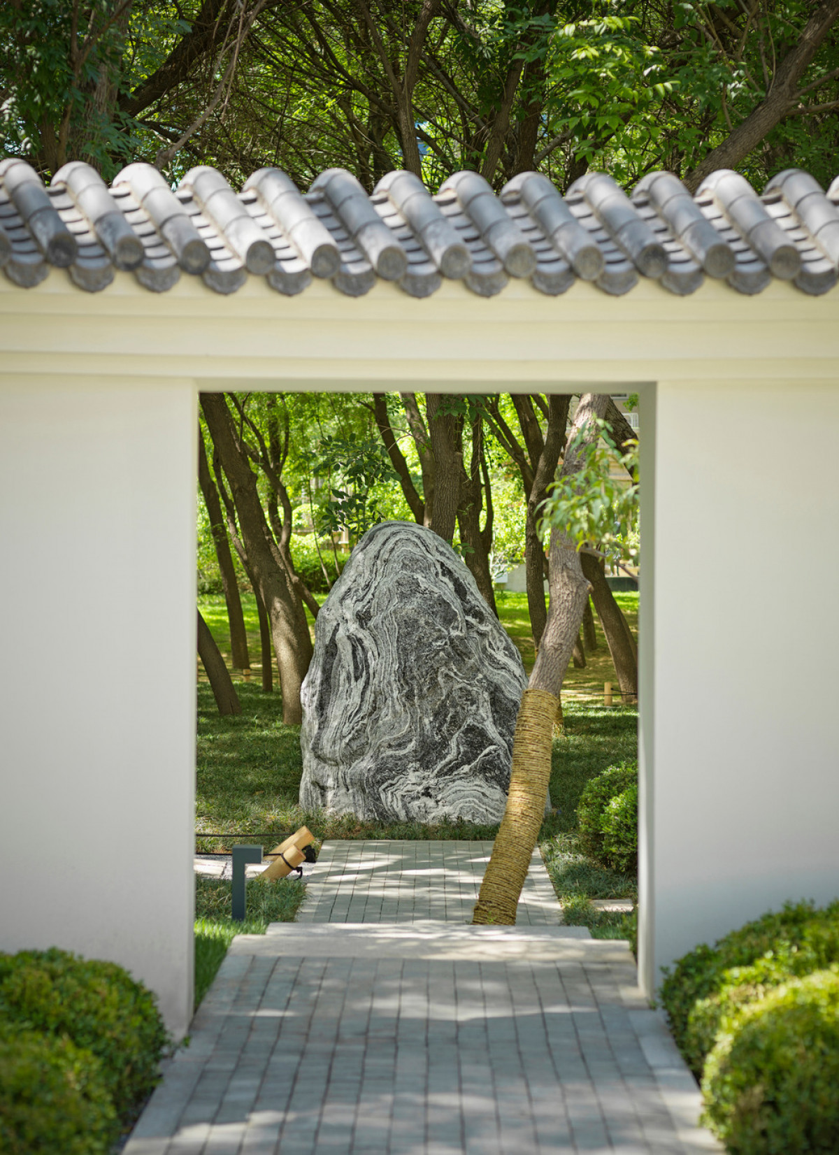 In Chinese traditional belief spirits move in straight lines. In traditional Chinese architecture and garden design walls are often utilized to block spirits from entering in directly. Here a sculptural stone which also serves as a focal point along the p