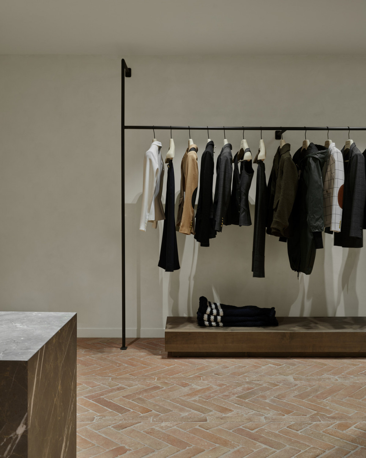 Rectangular volumes at each clothing rack's base help frame to the garments.