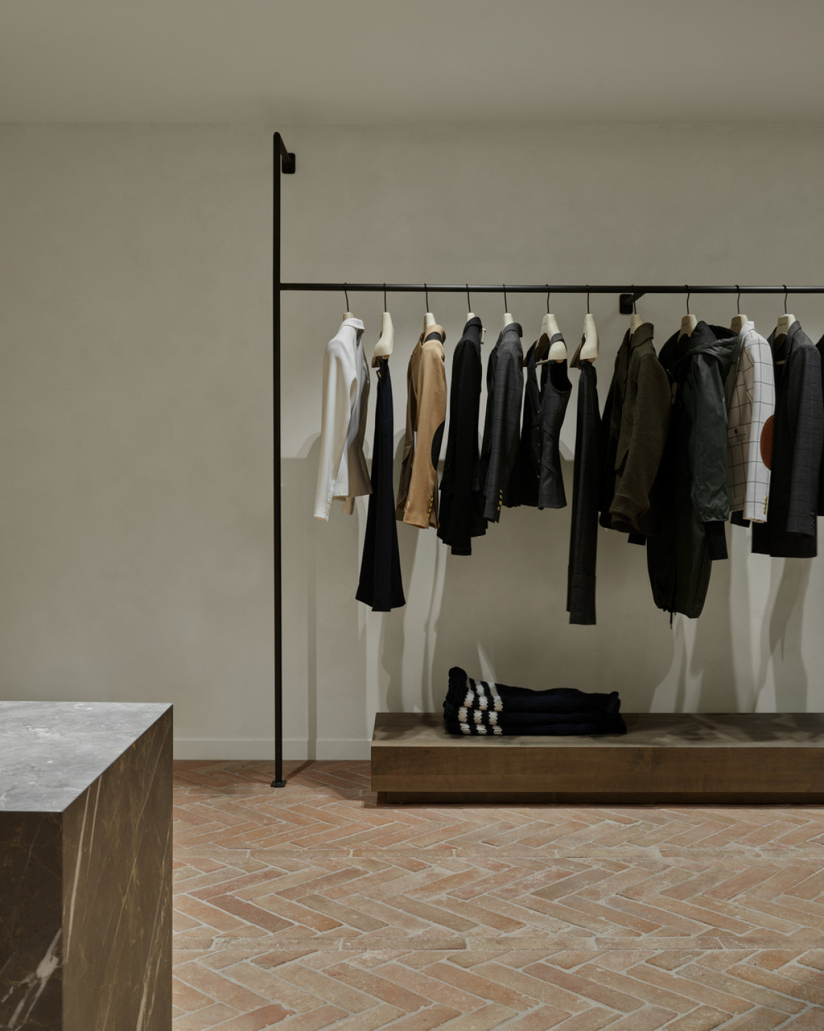 Rectangular volumes at each clothing rack's base help frame to the garments.